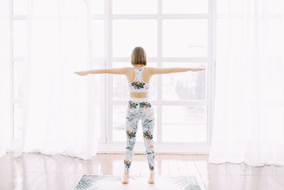 Girl in a sports uniform does exercises, physical exercises, yoga and stretches at home