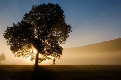 Silhouette of man running on field at sunrise