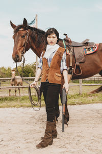 Portrait of woman standing with horse at ranch