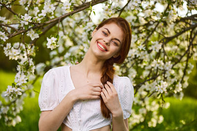 Portrait of young woman standing against plants