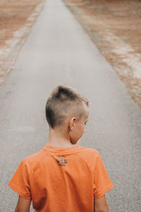 Rear view of boy on road in a forest