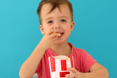 Young boy indoors eating fish and chips smiling