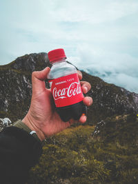 Midsection of woman holding red and mountain against sky