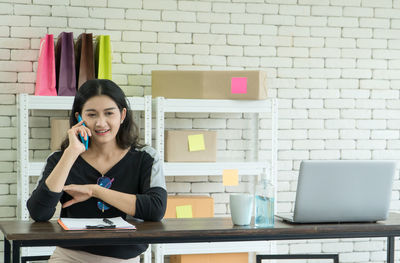 Portrait of young woman using phone while sitting on table