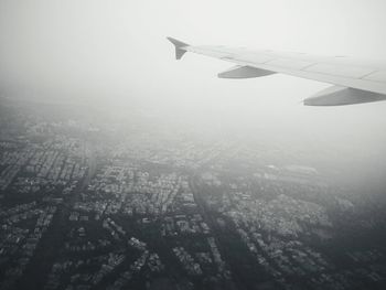 Aerial view of airplane wing over cityscape