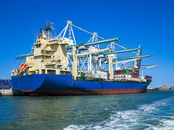 Cranes at commercial dock against blue sky