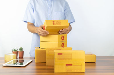 Midsection of woman holding box against white background