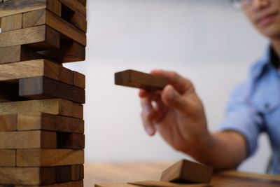 Cropped image of man stacking dominoes on table