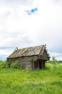 Wooden house on field against sky