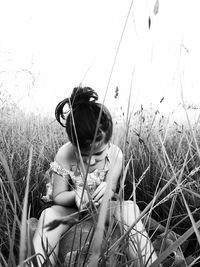 Full length of girl sitting on field against clear sky