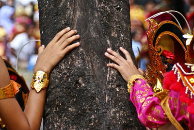 Close-up of couple hands on tree trunk