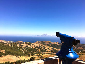 Scenic view of mountain with hand-held telescope against blue sky