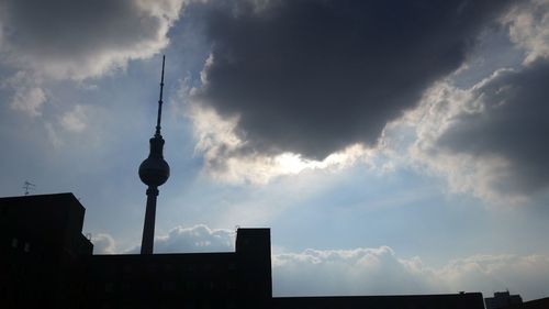 Low angle view of communications tower against cloudy sky