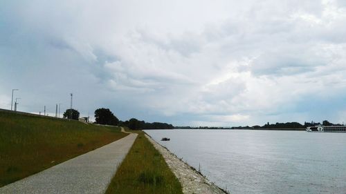 Road passing through landscape against cloudy sky