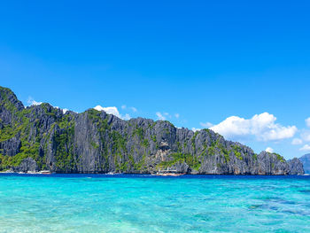 Scenic view of sea and rocks against blue sky