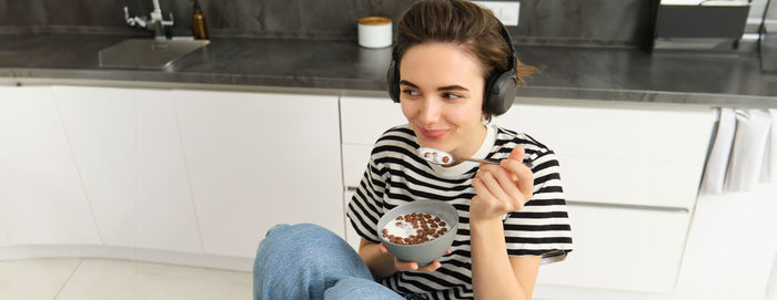 Portrait of young woman sitting on floor at home