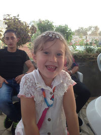 Portrait of smiling girl sitting against plants