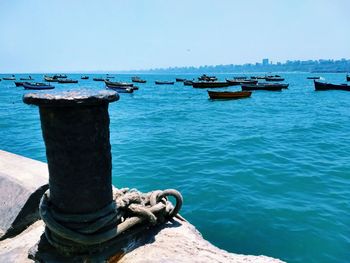 Close-up of boats moored at harbor against clear blue sky