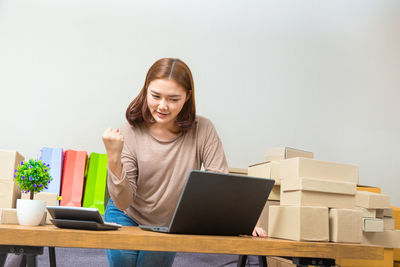 Young woman using phone while sitting on table