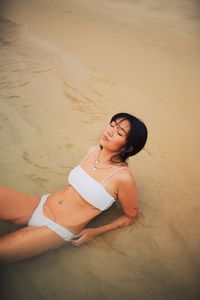 Sensuous young woman wearing bikini relaxing at beach