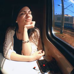 Woman day dreaming while sitting by window in passenger train