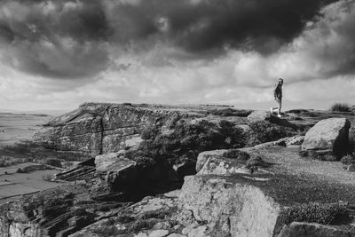 Man standing on cliff by sea against sky