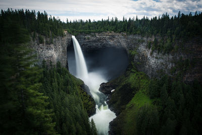 High angle view of waterfall against cloudy sky in forest