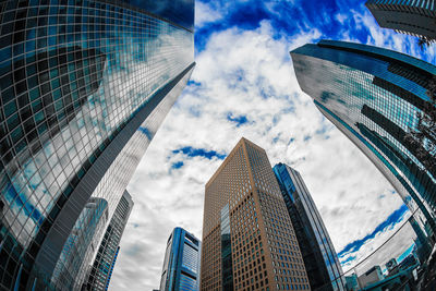 Low angle view of modern buildings against cloudy sky