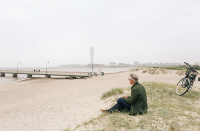 Man sitting on bicycle against clear sky