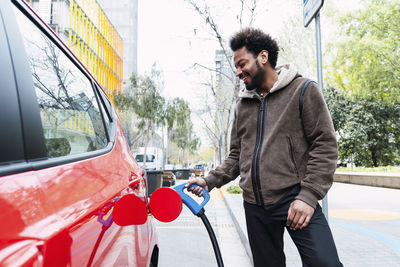 Happy man charging electric car at station