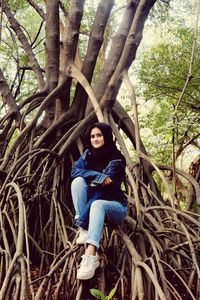 Portrait of teenage girl sitting on tree trunk