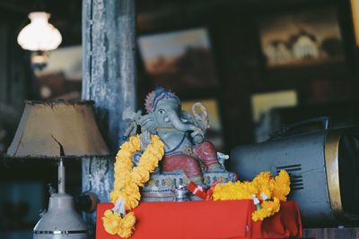 Close-up of floral garlands with ganesha sculpture on table