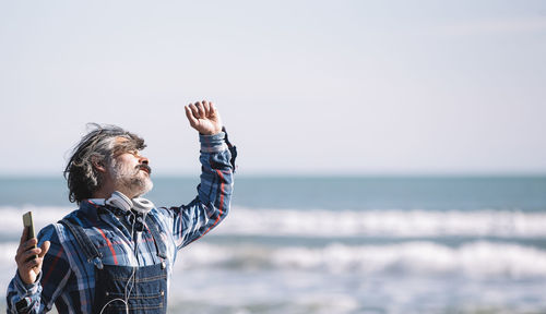 Portrait of a cheerful caucasian man in a hat enjoying at the beach on a sunny day in winter