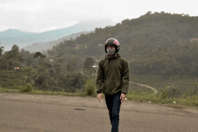 Young man wearing mask looking away while standing outdoors