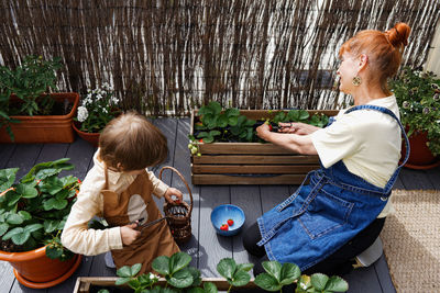 High angle view of mother and daughter standing by plants