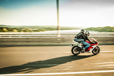 Man riding motorcycle with woman on road against sky