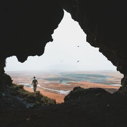 Man on rock by sea against sky