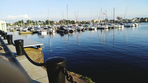 Sailboats moored on harbor against sky