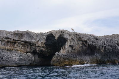 View of rock formation in sea against sky