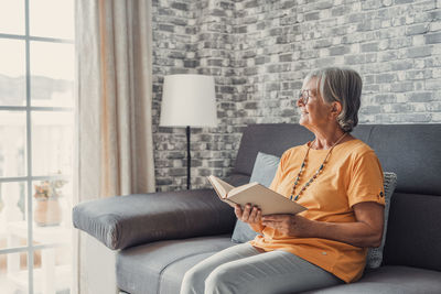 Young woman using laptop while sitting on sofa at home