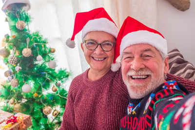Portrait of smiling senior couple with christmas tree at home
