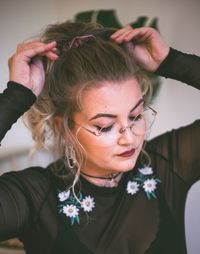 Close-up of beautiful woman tying hair at home