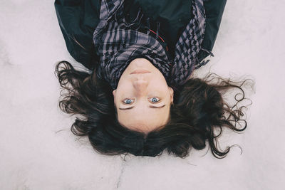 High angle portrait of young woman lying on snow