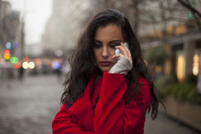 Young woman talking on mobile phone while standing on city street