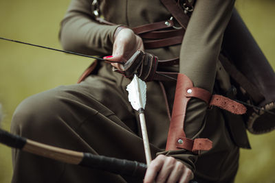 Midsection of woman holding bow and arrow