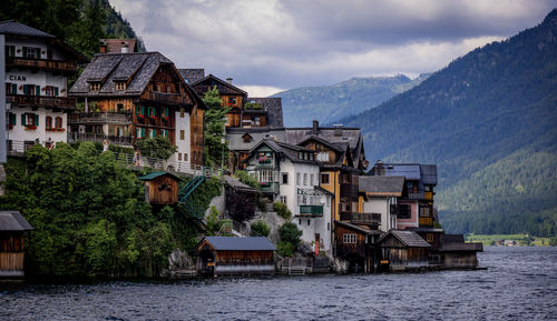 Buildings by river against sky