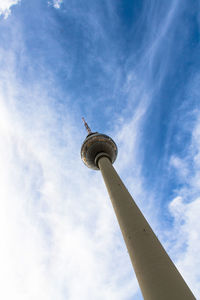 Low angle view of communications tower against cloudy sky