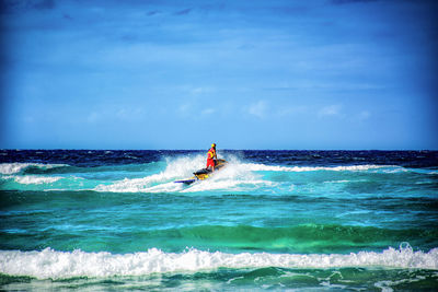 Man surfing in sea against sky