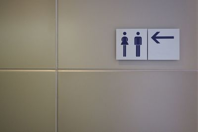 Close-up of restroom signs on tiled wall