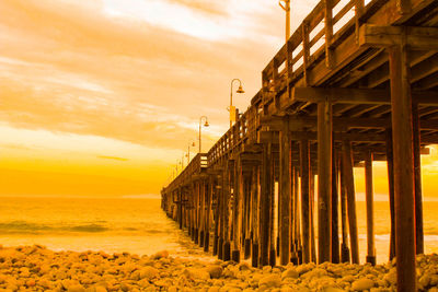 Pier over sea against sky during sunset